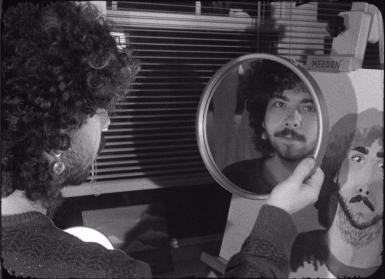 Ty Vinson looks into a mirror while painting a portrait of himself