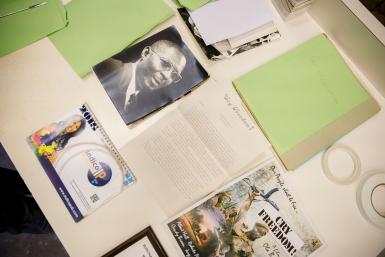 An assortment of documents, including a black and white headshot of a man and a movie poster, are arranged on a table.