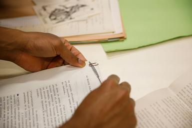 Closeup of hands removing a paperclip from a group of papers