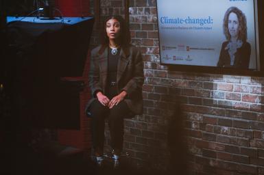 Beverly Thompson sits in a chair in the Beckley Studio in front of a monitor displaying a photo of Elizabeth Kolbert.