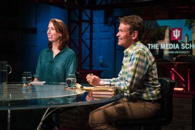 Suzannah Evans Comfort and Gabriel Filipelli sit at a news desk in the Beckley Studio.