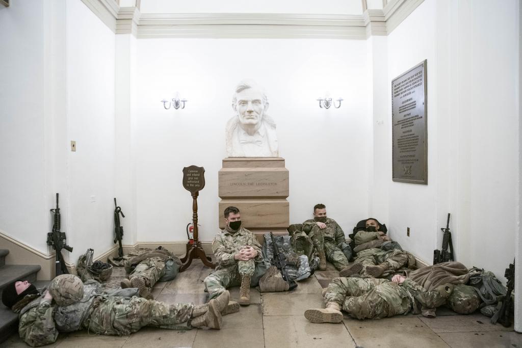 Soldiers in fatigues lie on the ground in front of the Lincoln the Legislator statue..