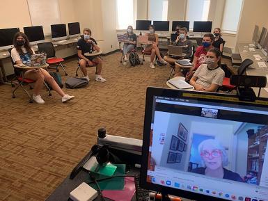 A classroom of students watching a guest speaker on Zoom