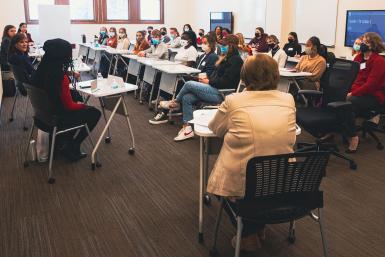 Students in a clasroom listen to a panel of alumni.