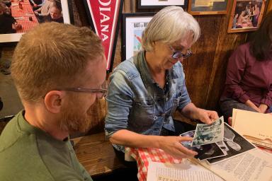 Ginny Hingst showing Josh Bennett some photographs in a booth at Nick's