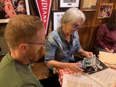 Ginny Hingst showing Josh Bennett some photographs in a booth at Nick's