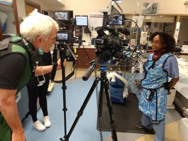 A journalist interviews a medical professional inside an operating room.