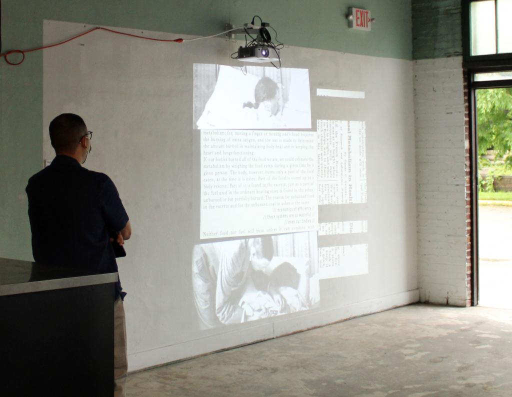 A man watching a video installation of medical photos being projected onto a wall.