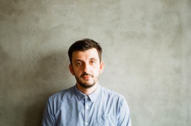 Stas Menzelevskyi headshot. Man with beard wearing blue shirt looks to the camera.