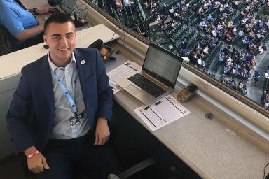 A man in a black suit sits in a press box