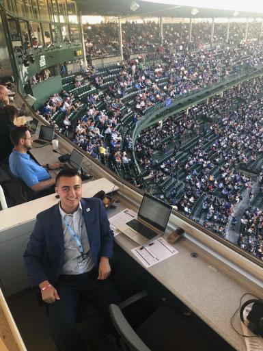 A man in a black suit sits in a press box