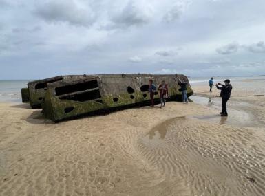 A man photographs a submarine on the beach.