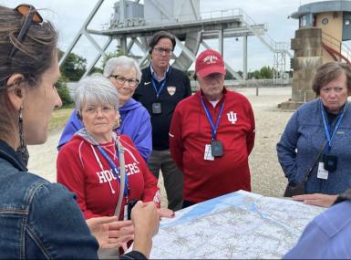 The group examines a map while visiting the beaches of Normandy.