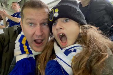 A man and his son pose for a photo at a Leeds United match in Leeds United gear