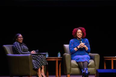 Adara Donald and Nikole Hannah-Jones sit on stage smiling with their faces toward the crowd.