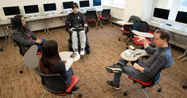 four people sit in a circle in a classroom talking