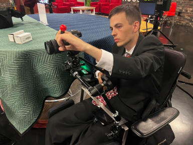 a man in a wheelchair uses camera equipment 