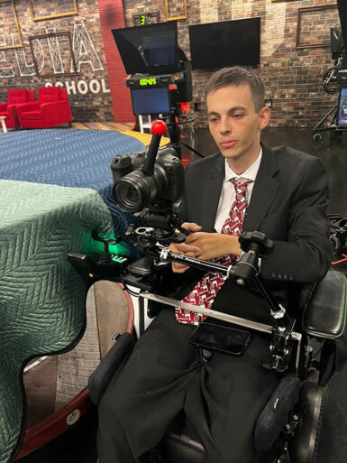 a man in a wheelchair uses camera equipment 