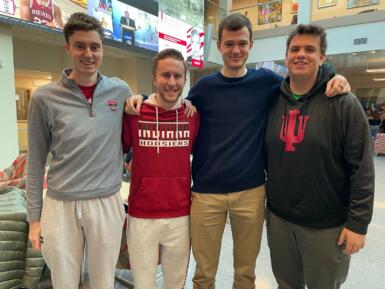 Four students stand in the Franklin Hall commons smiling at the camera