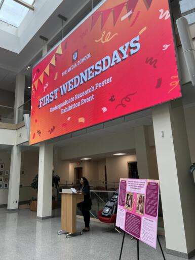 The screen in the Franklin Hall commons reads "First Wednesdays" with a red-and-orange background that also displays animated confetti.