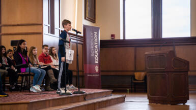 a boy on a stage speaks into a microphone