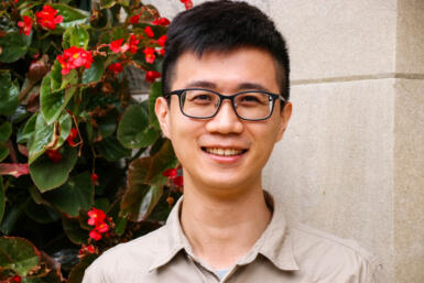 Headshot of Bevis Chen with stone wall and greenery behind