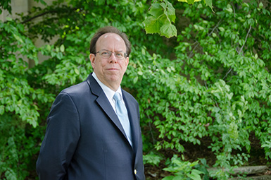 Headshot of Anthony Fargo standing in front of greenery with arms behind his back