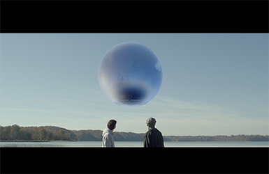 Screen capture from "The Black Sphere" with a human and an alien standing before a floating silver ball.