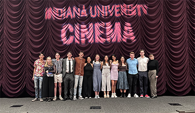 Students of IU Cinema stand in front of a curtain for photo.