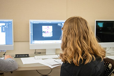 An HSJI student sits at a computer with Adobe Photoshop pulled up.
