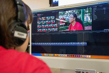 An HSJI student edits a video interview at a computer.