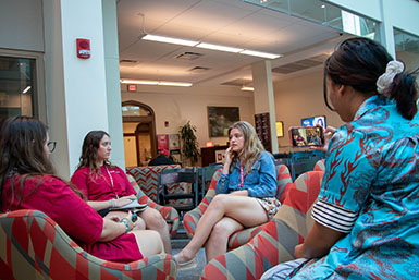 HSJI students sit in chairs in Franklin Hall Commons, interviewing a Media School student.