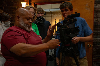 Bear Brown adjusts a camera while three students watch.