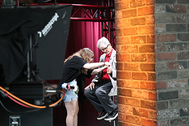 A student adjusts the microphone on actor Eric Roberts's jacket.