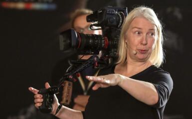Claudia Raschke holds a camera while she points and talks.