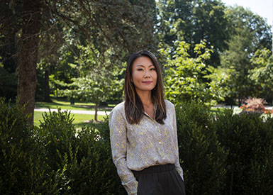 A headshot of associate professor Minjeong Kang, in front of greenery.