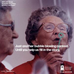 An ad featuring two elderly ladies. The one on the left is blowing bubbles. Text reads: "Just another bubble blowing contest. Until you help us fill in the story. Monroe County History Center."