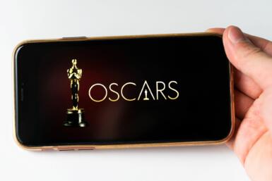 Close up of a person holding a phone sideways with "Oscars" spelled out next to an Academy Award statue.