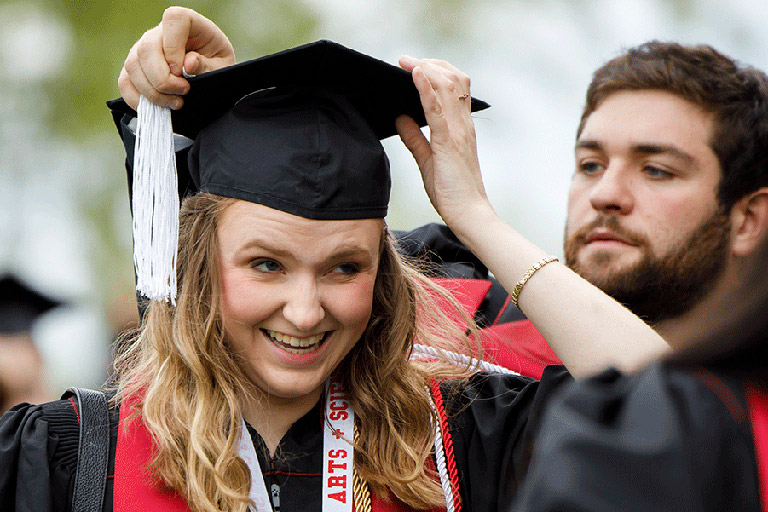 Student putting on cap at commencment ceremony