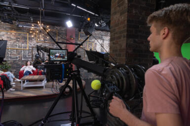 Ashton Hackman operates a camera in a studio.