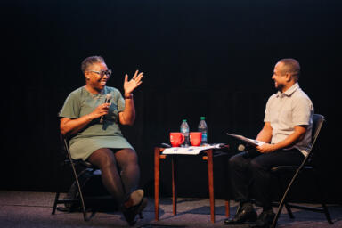 Novotny Lawrence and Robin R. Means Coleman sit on the stage and speak to audience.