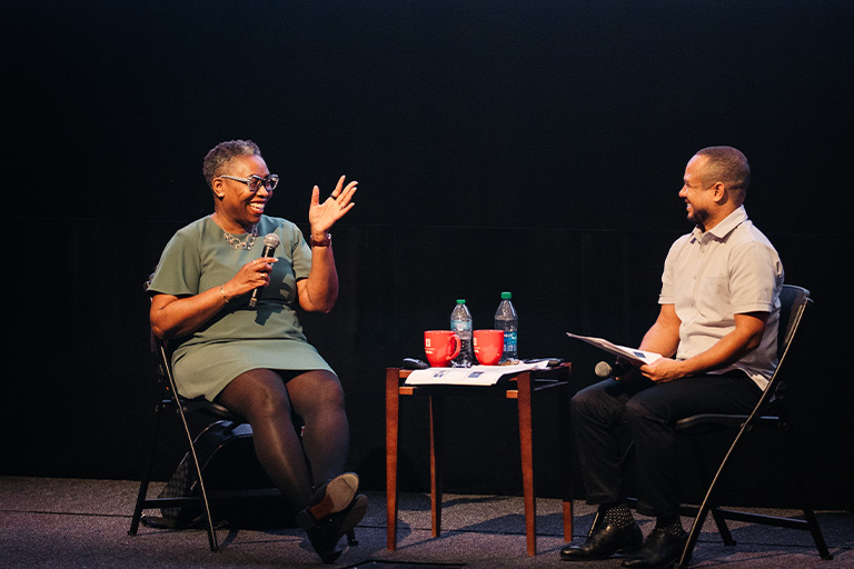 Novotny Lawrence and Robin R. Means Coleman sit on the stage and speak to audience.