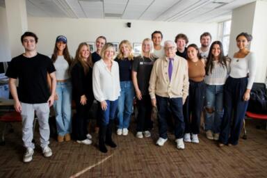 Group of people stand together in a classroom.