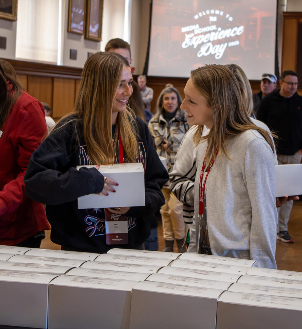 Two students smile at each other while holding boxed lunches.