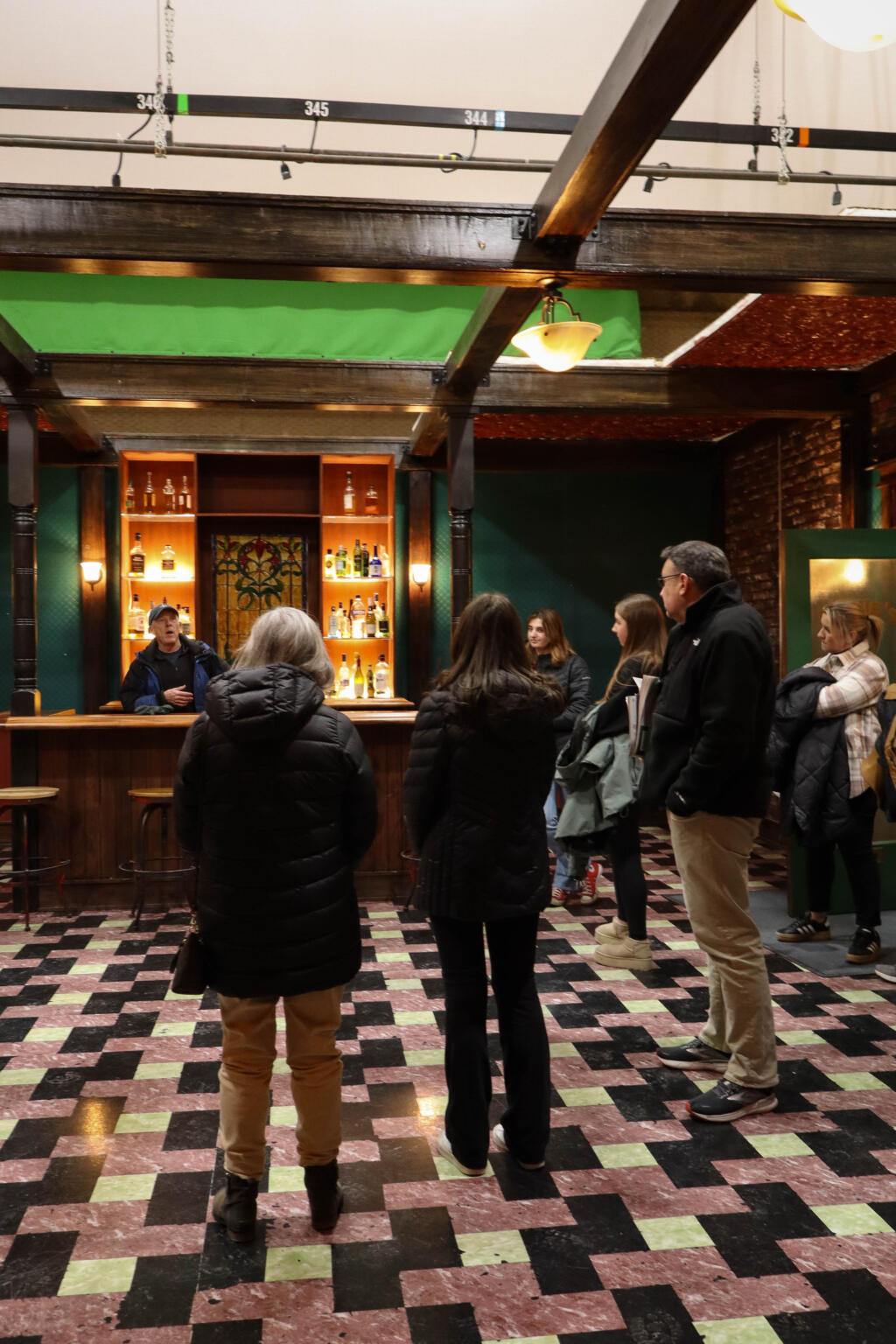 People stand around a movie set of a bar.