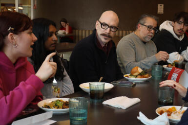 David Tolchinsky and Gerry Lanosga sit at a table and chat with students.