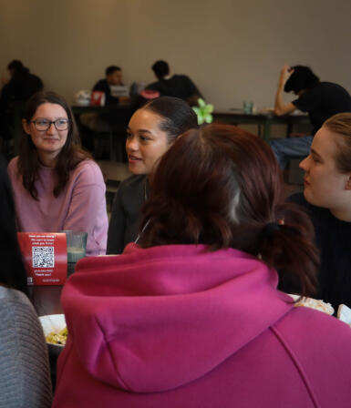 Students sit at a table and talk together.