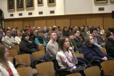 A large audience is seated in Presidents Hall in Franklin Hall.