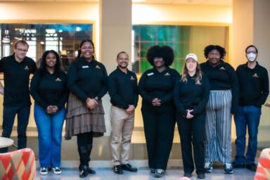 Group of people stand in a line posing for the camera.