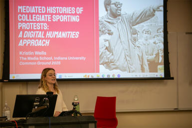 Phot of Kristen wells speaking on the topic "Meditated histories of collegiate sporting protests: A digital humanities approach."